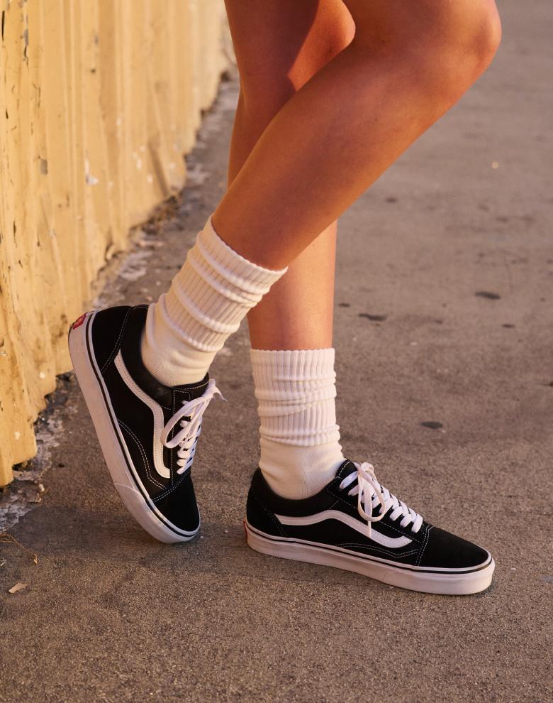 A pair of black Premium Old Skool shoes laying on top of music equipment cables.